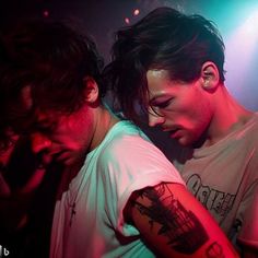 two men standing next to each other in front of purple and green lights on stage