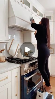 a woman standing on top of an oven in a kitchen next to a stove top oven