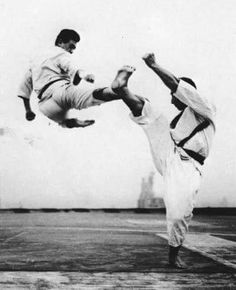 two men doing tricks in the air with their feet on each other's legs