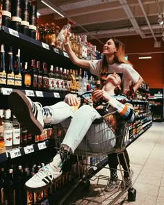 a woman is sitting in a shopping cart and she has her feet up on the shelf