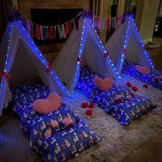 three teepee tents with blue lights and pillows on the floor next to each other