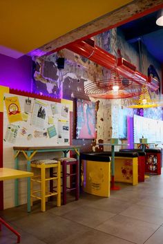 the interior of a restaurant with brightly colored tables and stools