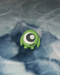 a green toy with an evil eye on top of some blue and white foamy material