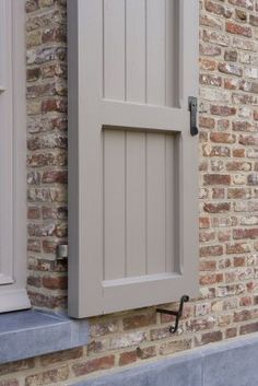 an open window on the side of a brick building with shutters and a door