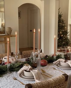 a dining room table set for christmas with candles and decorations on the table in front of it