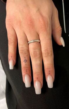 a woman's hand with white nails and a ring on her left finger, wearing a diamond band