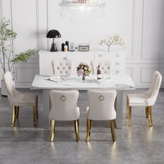 a dining room table with white chairs and a chandelier