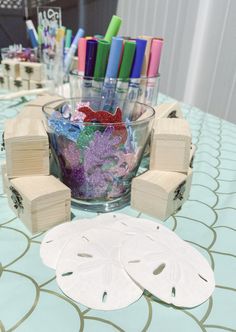 a table topped with lots of crafting supplies on top of a blue table cloth