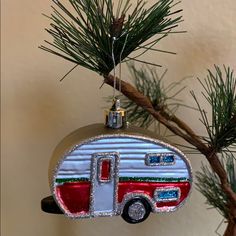 an ornament shaped like a camper is hanging from a pine tree branch