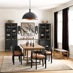 a dining room table and chairs in front of a black bookcase with pictures on the wall