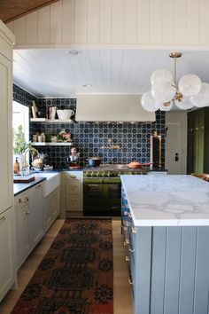 a kitchen with an area rug in front of the sink and stove, along with several hanging lights