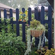 a blue picket fence with flowers and plants growing on it