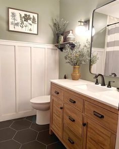 a white toilet sitting next to a sink in a bathroom under a large mirror above a wooden cabinet