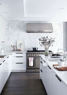 a modern kitchen with white cabinets and stainless steel stove top oven, dishwasher, and microwave