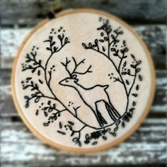 an embroidered deer with leaves and branches on it's back is sitting on a wooden surface