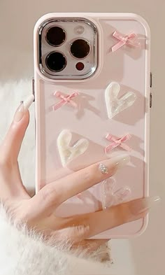 a woman's hand holding an iphone case with hearts and bows on the back