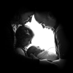 a man and woman holding a baby in their arms while looking down at the ground