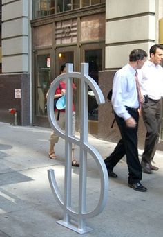 two men walking down the sidewalk in front of a sign that says $ on it