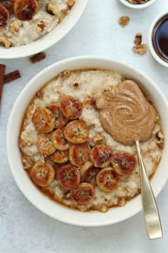 two bowls filled with oatmeal topped with bananas and nuts next to cinnamon sticks