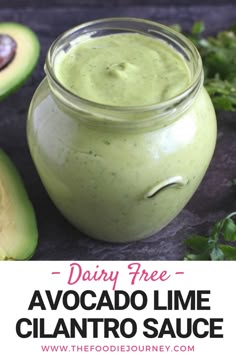 avocado lime cilantro sauce in a glass jar next to sliced avocados