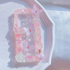 a cell phone case with pink flowers and butterflies on it sitting on a white surface