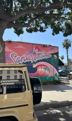 a truck parked next to a tree in front of a building with graffiti on it