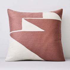 a red and white pillow with an abstract design on the front, sitting on a table