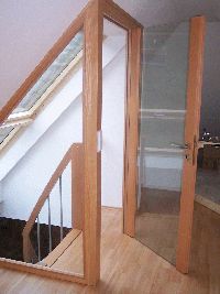 an empty room with wooden floors and glass doors leading to the upper floor, next to a stair case