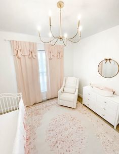 a baby's room with a white crib, dresser and pink drapes