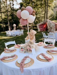 a teddy bear sitting on top of a table with plates and place settings in front of it