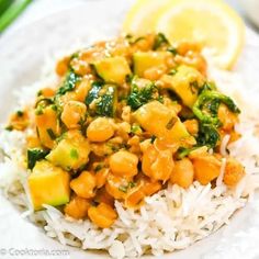 a white plate topped with rice and chickpeas next to a slice of lemon