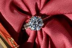 a diamond ring sitting on top of a red cloth