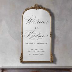 a welcome sign hanging on the wall next to a mantle with a vase in it