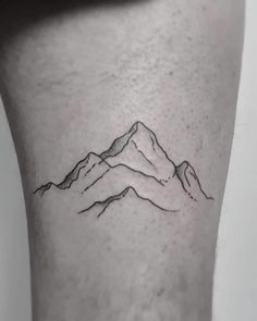 a small mountain tattoo on the right side of the leg, with mountains in the background