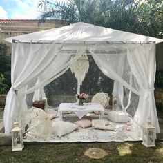 a white canopy bed sitting on top of a lush green field