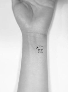 a hand with a small sheep tattoo on it's left wrist and the word love written in black ink