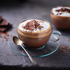 two cups filled with hot chocolate and topped with whipped cream