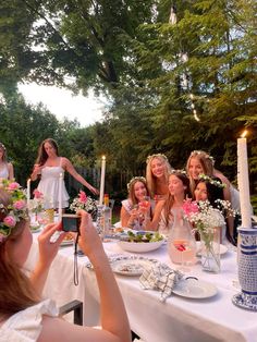 a group of women sitting around a table with plates and flowers in front of them