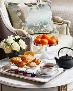 a tray filled with croissants, oranges and tea on top of a table