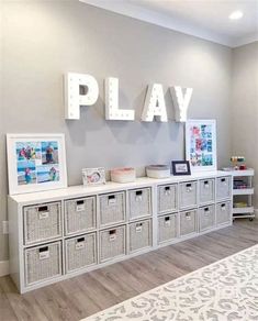 a playroom with white storage bins and pictures on the wall