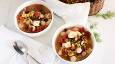 two white bowls filled with soup and vegetables