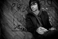 a man sitting on top of a wooden floor next to a wall with graffiti written on it