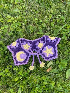 a purple and yellow crocheted hat laying in the grass