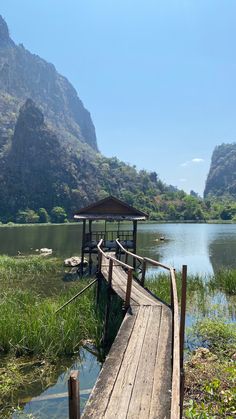 a wooden dock sitting on top of a lake next to a lush green mountain range