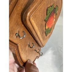 a hand holding a wooden case with leaves on it