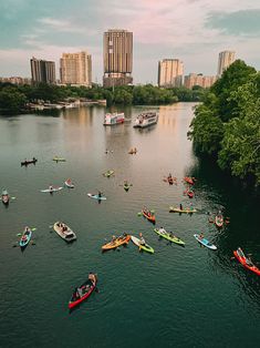 a group of kayakers are floating on the water in front of large city buildings