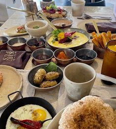 an assortment of breakfast foods on a table with utensils and cups in front of them