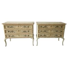 a pair of white chests with drawers on each side and an ornate design at the top