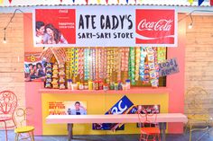 a booth with coca - colas and chairs in front of it