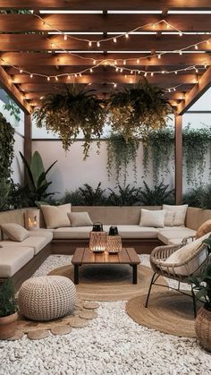 an outdoor living room with lots of plants and lights on the ceiling, couches and tables